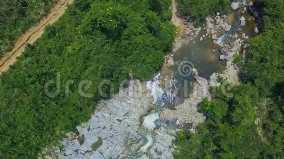 Flycam在丛林中的石头间靠近干净的河塘视频的预览图