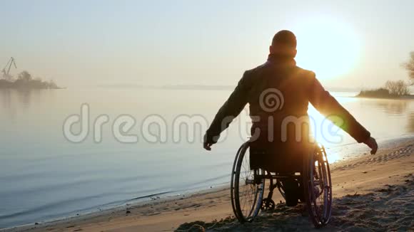 轮椅上的瘸子双手举起日落孤独的残疾人视频的预览图