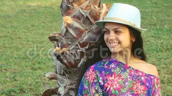 夏天一个皮肤黝黑的年轻女人长发坐在热带棕榈树下视频的预览图