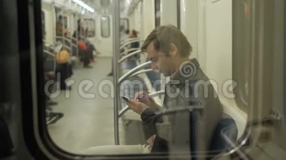 年轻英俊的商人地铁里有智能手机地下火车站的男学生公共场合视频的预览图