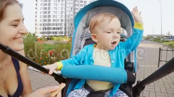 一岁男孩坐在婴儿车里吃饼干的肖像视频的预览图