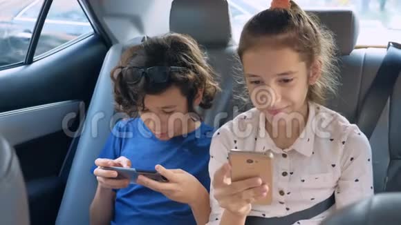 双胞胎兄妹在车里旅行时用电话视频的预览图