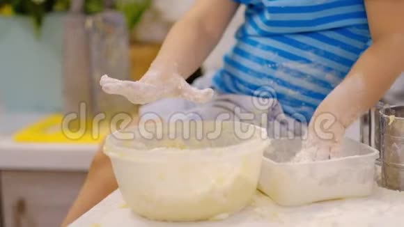 小男孩在桌子上准备面团打喷嚏小宝宝玩面粉面包师准备面团视频的预览图