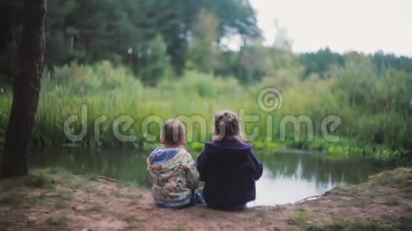 两个小孩一个女孩和一个男孩坐在河岸上一个女孩在吃西瓜他们回头看回顾视频的预览图