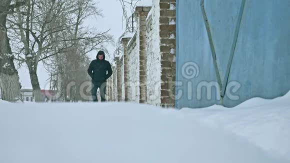 冬天人们穿过一座古老的砖围栏的雪城冬天穷人在雪地里散步视频的预览图