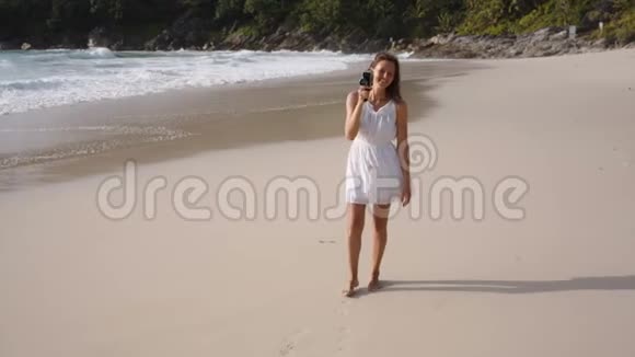 年轻女子在海滩上使用老式相机视频的预览图