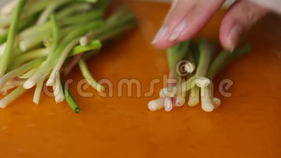 把樱桃用刀切在橙色的砧板上女性用手切韭菜做菜特写视频的预览图