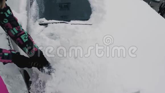 一个女人在冬天用刷子清洁她的车视频的预览图