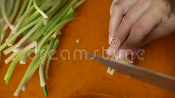 把樱桃用刀切在橙色的砧板上女性用手切韭菜做菜特写视频的预览图