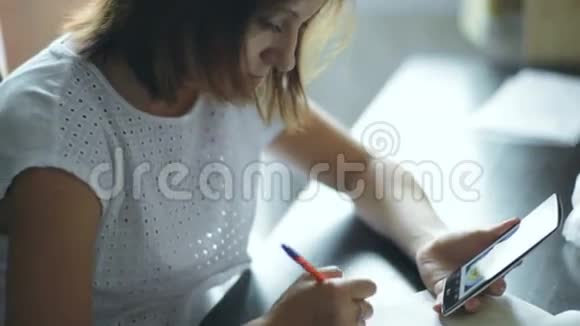 年轻女子在笔记本上写字视频的预览图