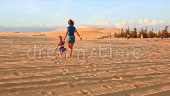 在日落时分妈妈和小女孩一起在沙丘上散步视频的预览图