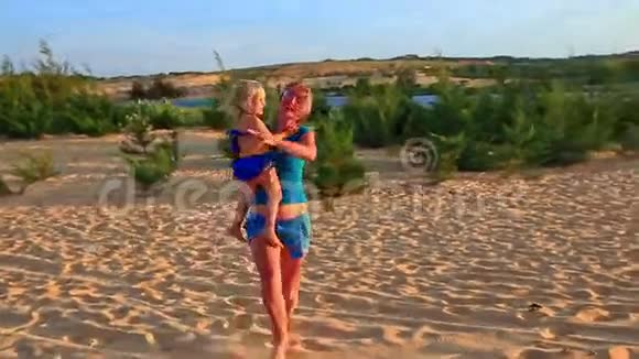 母亲骑着小女孩的武器在沙丘上展示日落时的吉普车视频的预览图
