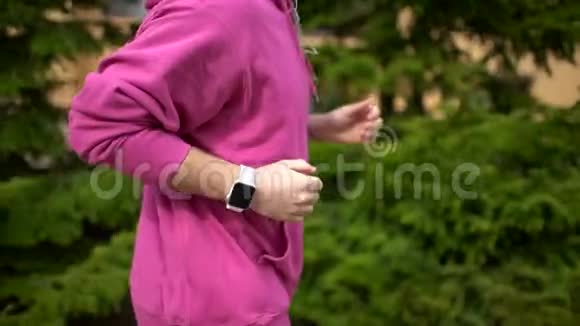 男人在森林森林里跑步训练看智能手表户外跑步的人视频的预览图