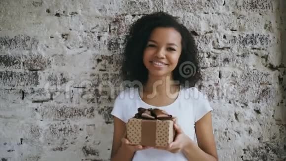 年轻的非洲裔美国妇女拿着礼品盒微笑着对着镜头的肖像视频的预览图