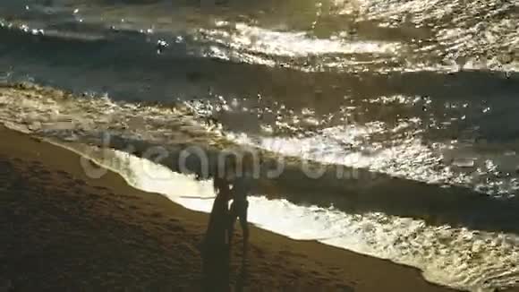 在夕阳西下的海滨亲吻几个吻就像海浪拍打着它们附近的沙质海岸线视频的预览图