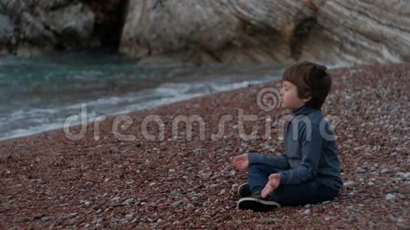 小男孩坐在户外海边冥想视频的预览图