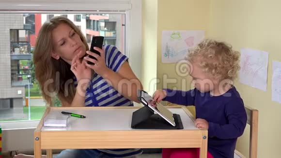 年轻漂亮的女人用智能手机给女儿和自己拍照视频的预览图