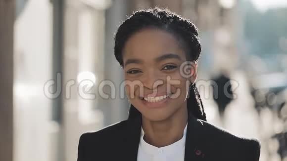 站在老街背景上的时尚非洲商业女性的肖像她看着摄像机微笑着视频的预览图