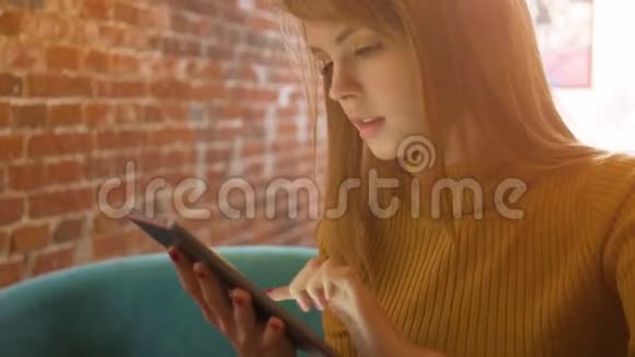优雅的年轻女子坐在舒适的咖啡店里在触摸板上聊天视频的预览图