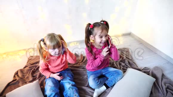 快乐的小女孩用智能手机娱乐坐在明亮的房间里墙上有花环视频的预览图