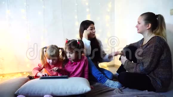 女人和女婴四人交流忙于自己的事情坐在墙上的背景上墙上挂着花环视频的预览图