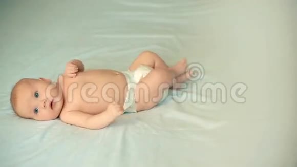 可爱的宝宝美丽的蓝眼睛躺在白色的床上视频的预览图