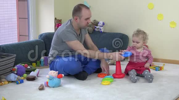 父亲和宝贝女儿在房间里玩五颜六色的塔4K视频的预览图