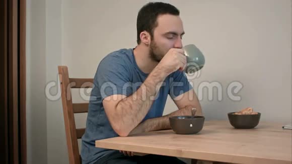 伤心沮丧的男人坐在餐桌旁喝茶视频的预览图