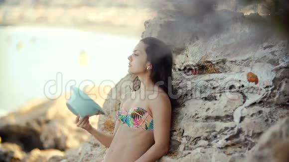 在海边的岩石附近留着长发的年轻女子视频的预览图