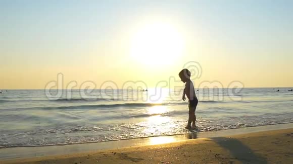 男孩在日落时在海边跳跃视频的预览图