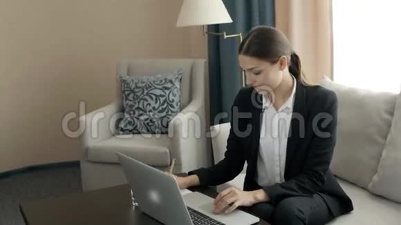 年轻女子在现代办公桌上工作手提电脑忙于远程学习在酒店房间女老板视频的预览图