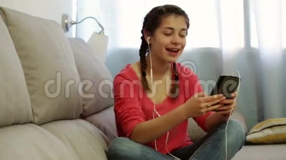 年轻女子在家里用电话听音乐视频的预览图