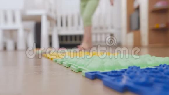 幼儿园里的一个小孩赤脚走在按摩垫上踩在一个带刺的表面上视频的预览图