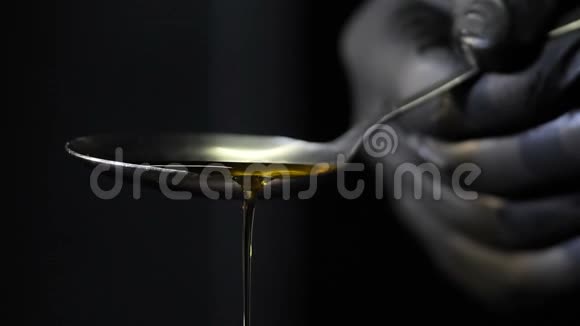 橄榄油在黑色背景上倒入勺子视频的预览图