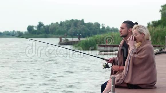清晨情侣们一起在湖上钓鱼男人在码头上拿着鱼竿坐着情侣们在码头上相爱视频的预览图