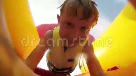 4K视频小男孩在充气滑梯旁快速滑入水池脸前有活动摄像头视频的预览图