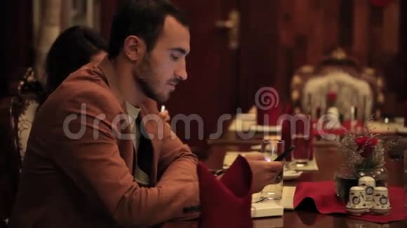 一对情侣在船上的餐馆里用智能手机视频的预览图