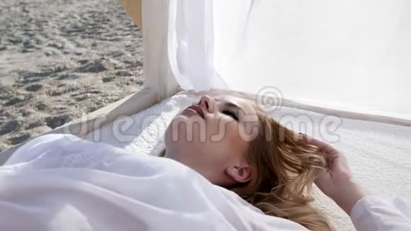 女孩躺在白色的窗帘上年轻的女性在海滩上异国的水果视频的预览图