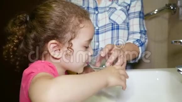 女孩吃完后仔细刷牙妈妈教她女儿吃饭后如何清洁和漱口视频的预览图