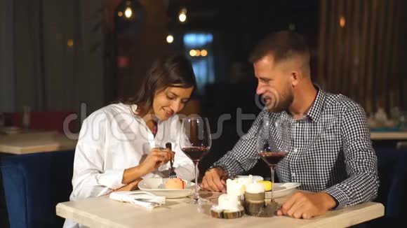 恋爱中的漂亮夫妇正坐在咖啡馆里喝咖啡吃奶酪蛋糕年轻女子正在喂她的男人视频的预览图