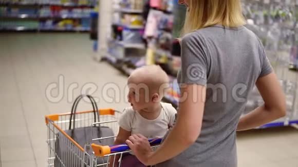 一位年轻的母亲带着她的小宝宝坐在超市的购物车里推着购物车向前走选择视频的预览图