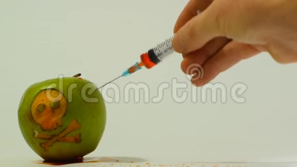 注射器插入一个绿色苹果与雕刻的头骨代表性的图像使用转基因物质在食品中视频的预览图