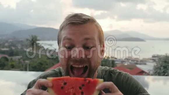 开朗的男人吃西瓜背景海景视频的预览图