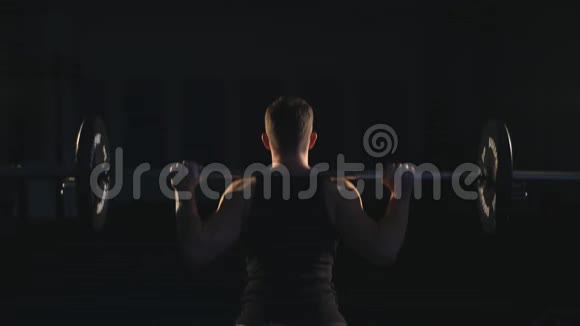 漂亮的举重运动员训练自信的肌肉男训练蹲与杠铃超过头部视频的预览图