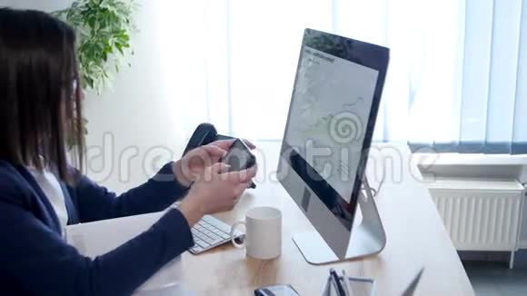 在办公室内部工作的年轻商务女性手持智能手机看屏幕可近距离观看视频的预览图