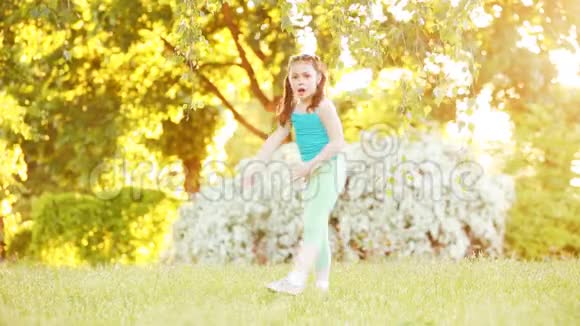 阳光明媚的夏日可爱的小女孩在公园的树下散步视频的预览图