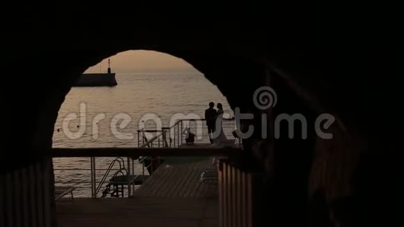 在拱门上新娘和新郎在海的背景下的剪影视频的预览图