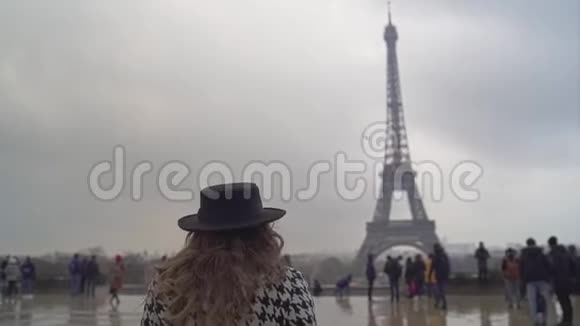 一位留着长发的年轻女孩在埃菲尔铁塔的前面走着微笑着视频的预览图