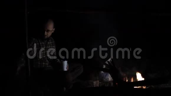 人在夜里把木头放在火上视频的预览图