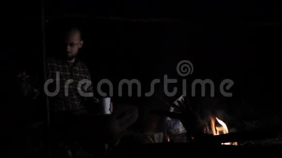 人在夜里把木头放在火上视频的预览图